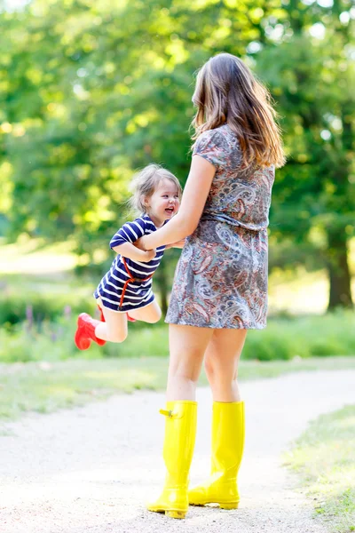 Мать и маленькая очаровательная девочка в резиновых сапогах веселятся — стоковое фото