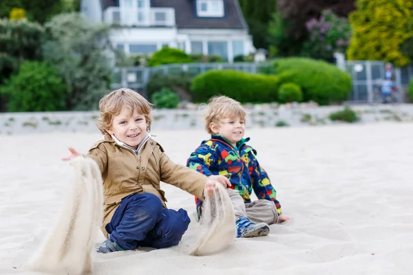 Two little children sitting on beach of river Elbe and playing t — Stock Photo, Image