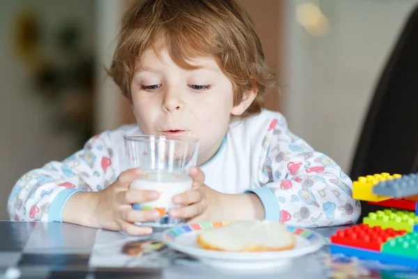 Liten unge pojke konsumtionsmjölk och leker med konstruktion block — Stockfoto