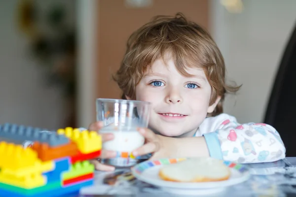 Liten unge pojke konsumtionsmjölk och leker med konstruktion block — Stockfoto