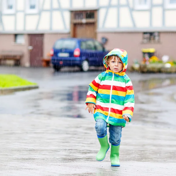 Gelukkig lachend jongetje wandelen in de stad door regen — Stockfoto