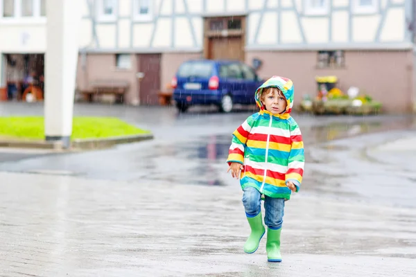 Gelukkig lachend jongetje wandelen in de stad door regen — Stockfoto