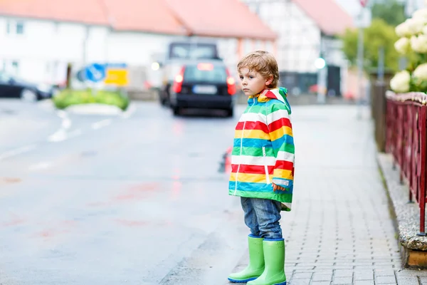 Feliz menino bonito andando na cidade através da chuva — Fotografia de Stock