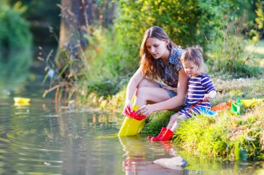 sevimli küçük kız ve annesi bir r kağıt tekneler ile oynarken