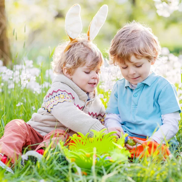 Два веселых друга детей в пасхальных кроликах во время охоты за яйцами — стоковое фото