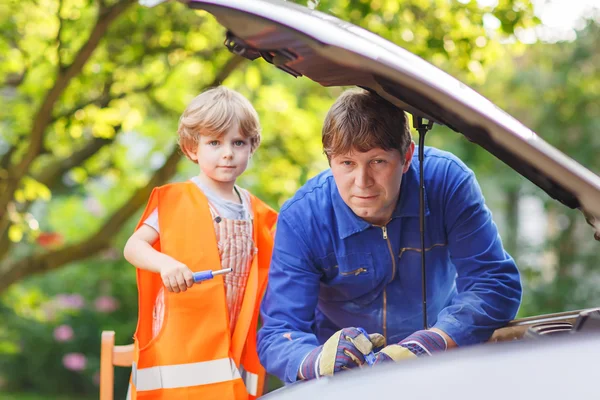 Jonge vader onderwijs zijn zoontje motorolie in famili wijzigen — Stockfoto