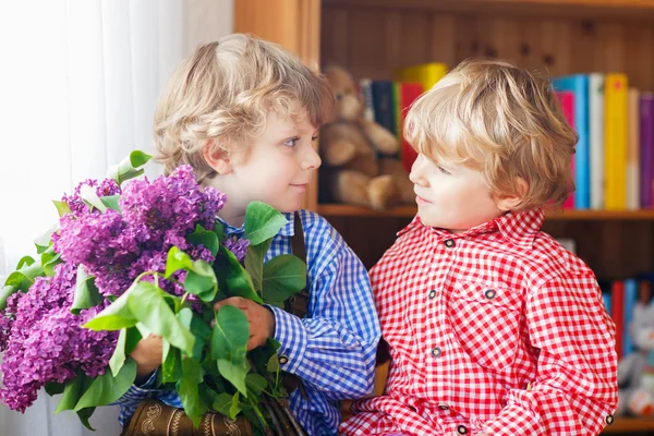 Two adorable little sibling boys with blooming lilac flowers — Stock Photo, Image