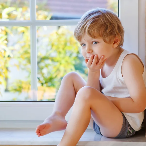 Niño de tres años mirando por la ventana en amarillo au —  Fotos de Stock