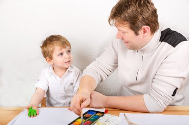 Küçük çocuk çocuk ve babası handpaints yapım ile eğleniyor