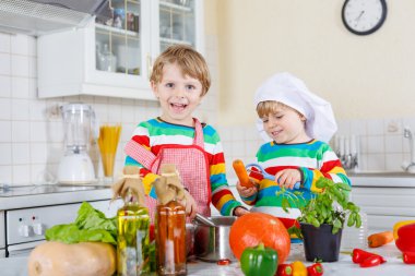 İki sevimli küçük çocuk İtalyan çorbası ve nitelikleri ile yemek pişirme