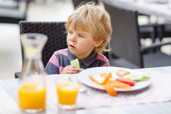 Liten unge pojke med hälsosam frukost i hotellets restaurang eller c — Stockfoto