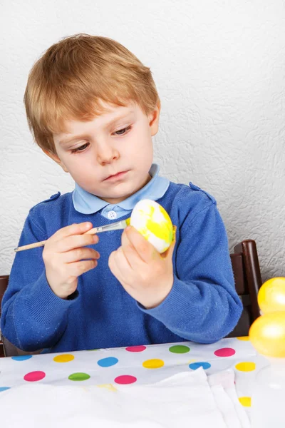 Piccolo bambino che dipinge uova colorate per la caccia di Pasqua — Foto Stock