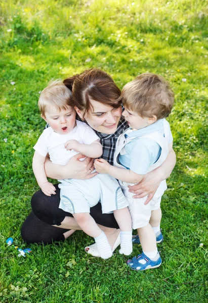 Glückliche dreiköpfige kaukasische Familie: junge Mutter und zwei kleine Geschwister — Stockfoto