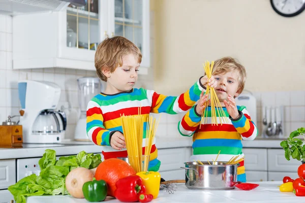 Duas crianças engraçadas cozinhar refeição italiana com espaguete — Fotografia de Stock