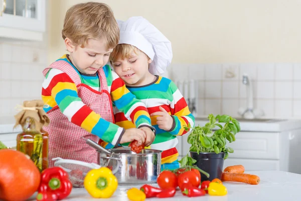 Два милых маленьких мальчика готовят итальянский суп и едят на огне. — стоковое фото