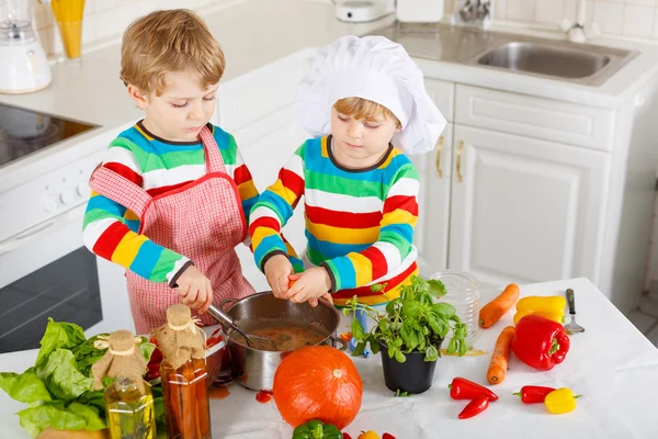 Gemelli che cucinano zuppa e pasto italiano con verdure fresche — Foto Stock