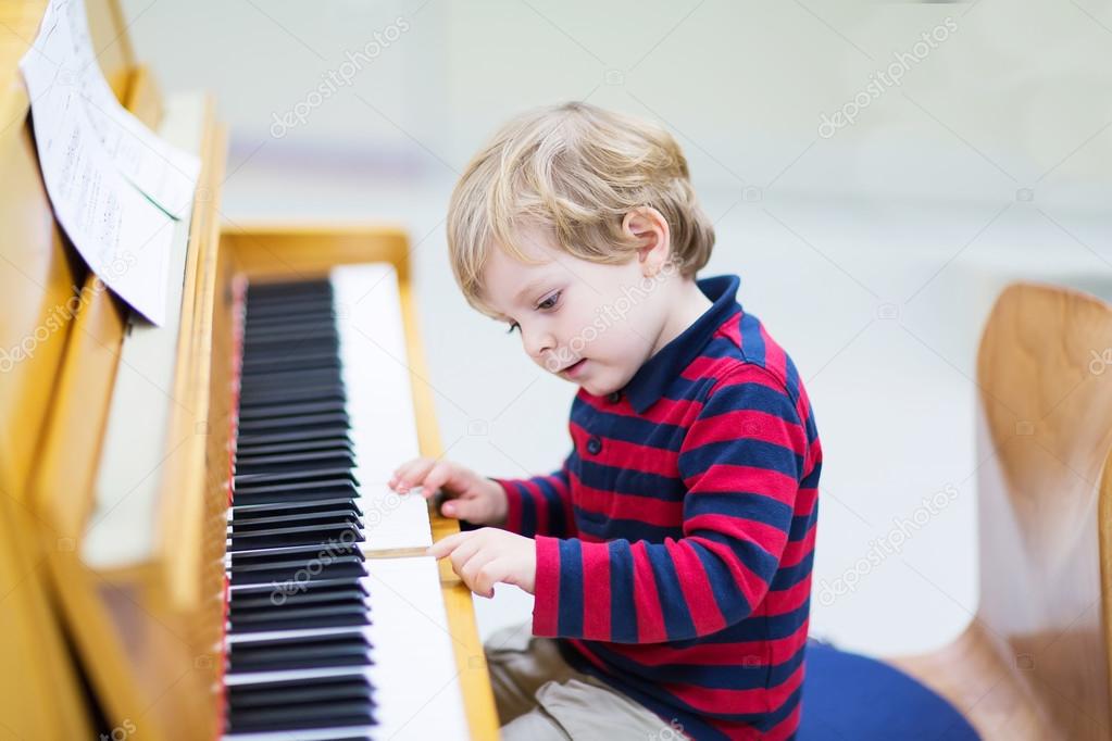 Two years old toddler boy playing piano, music schoool.