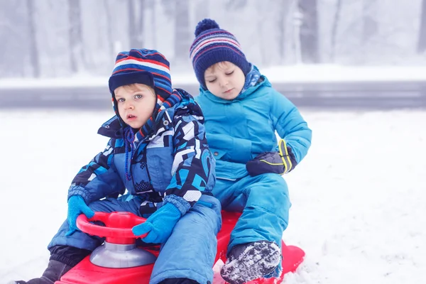 Boldog család: két kis twin fiú birtoklás móka-val hó (télen hólánc) — Stock Fotó