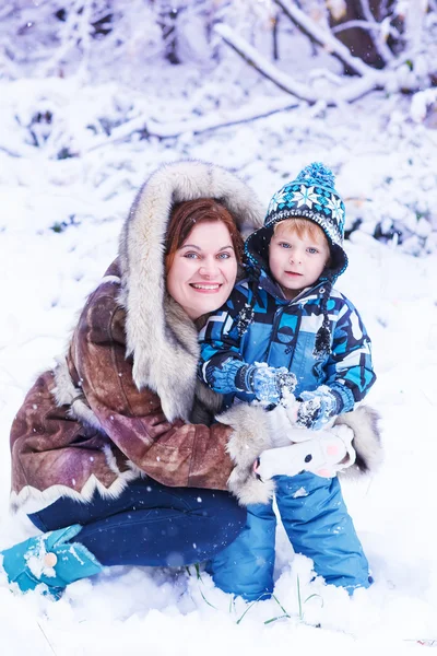Мать и малыш веселятся со снегом в зимний день — стоковое фото