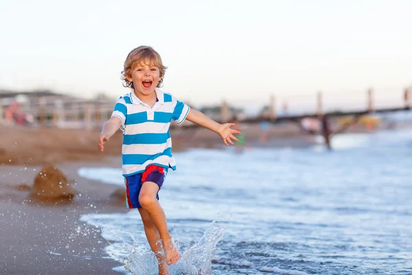 Happy little kid boy having fun with running through water in oc — Stock Photo, Image