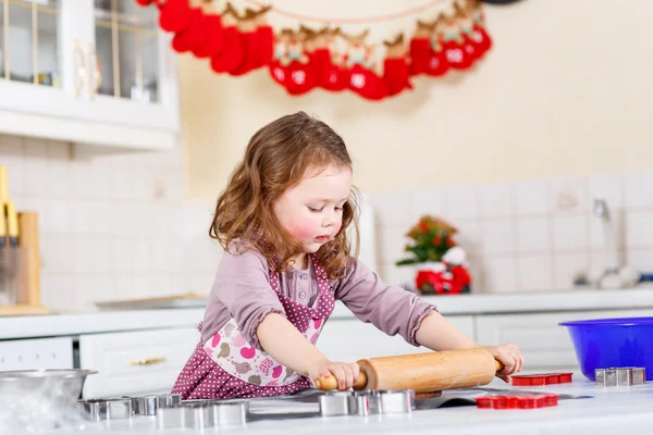 Malá holčička pečení perníku cookie v domácí kuchyni — Stock fotografie