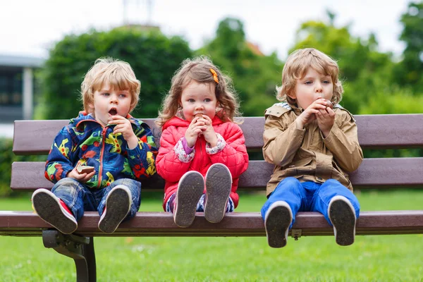 Two little boys and one girl eating chocolate — Stock Photo, Image