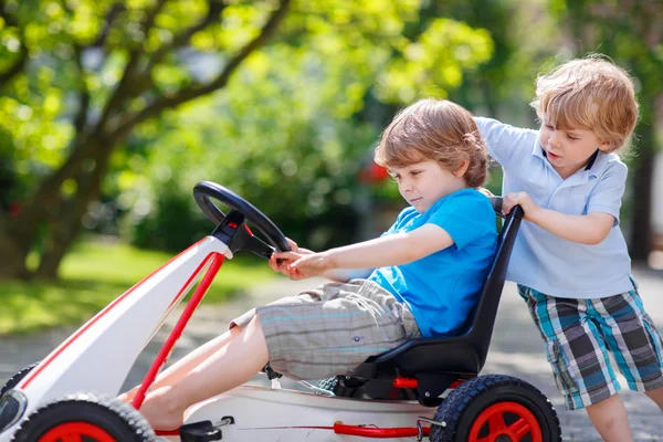 Dos niños felices hermanos divirtiéndose con coche de juguete — Foto de Stock