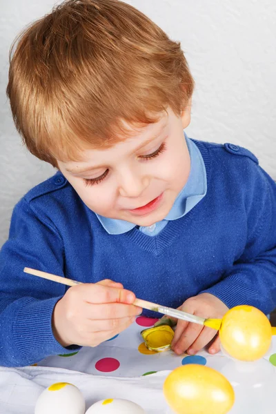 Piccolo bambino che dipinge uova colorate per la caccia di Pasqua — Foto Stock