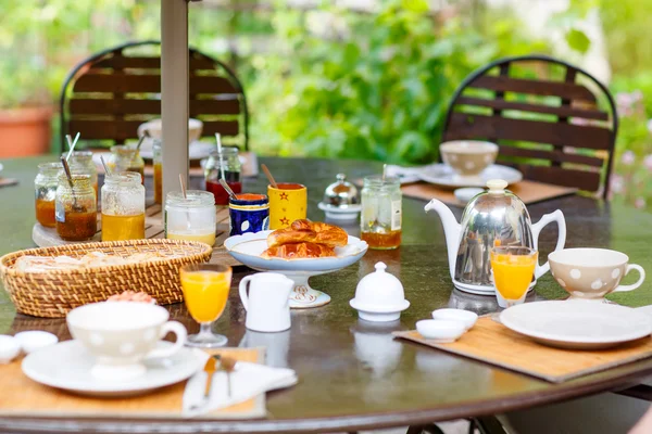 Mesa colocada para pequeno-almoço fora com várias compotas de café, crois — Fotografia de Stock