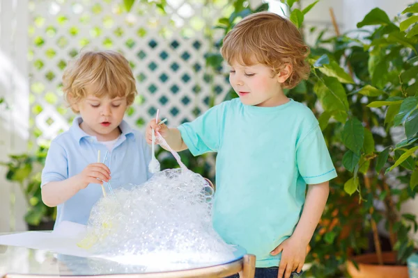 Two cute friend boys making experiment with colorful bubbles