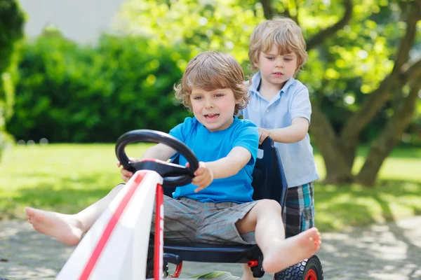 Zwei lustige kleine Jungen haben Spaß mit Rennwagen im Freien — Stockfoto