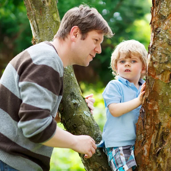 Roztomilý malý chlapec dítě těší, lezení na strom s otcem, předčit — Stock fotografie