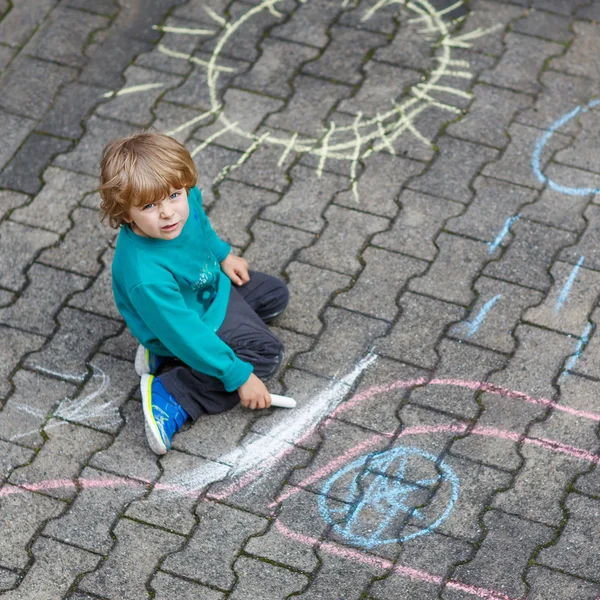 Kleiner blonder Junge malt mit bunten Kreiden im Freien — Stockfoto