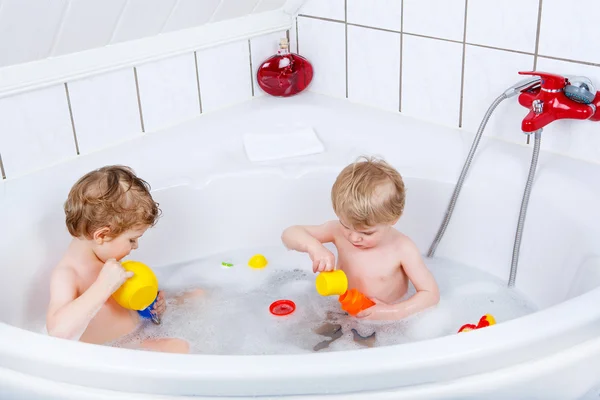 Dos niños hermanos divirtiéndose con agua tomando un baño en — Foto de Stock