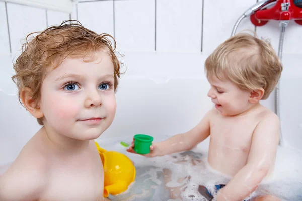 Dos niños hermanos divirtiéndose con agua tomando un baño en —  Fotos de Stock