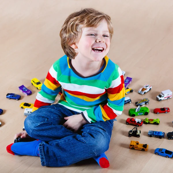 Funny little kid playing with lots of toy cars indoor. — Stock Photo, Image