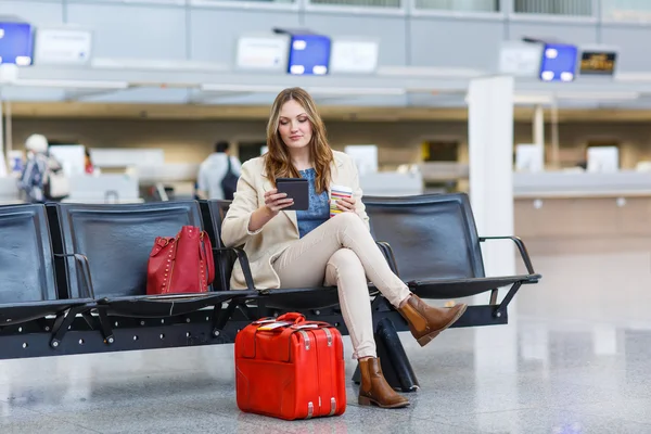 Женщина в международном аэропорту, читает электронную книгу и пьет кофе — стоковое фото