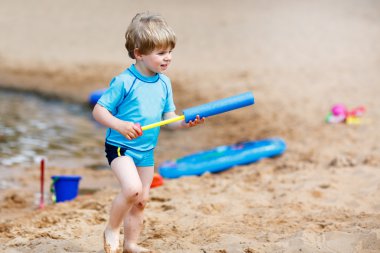 Küçük yürümeye başlayan çocuk su yakınındaki şehir lak ile eğleniyor