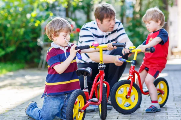 Padre enseñando a dos niños a reparar cadenas en bicicletas — Foto de Stock