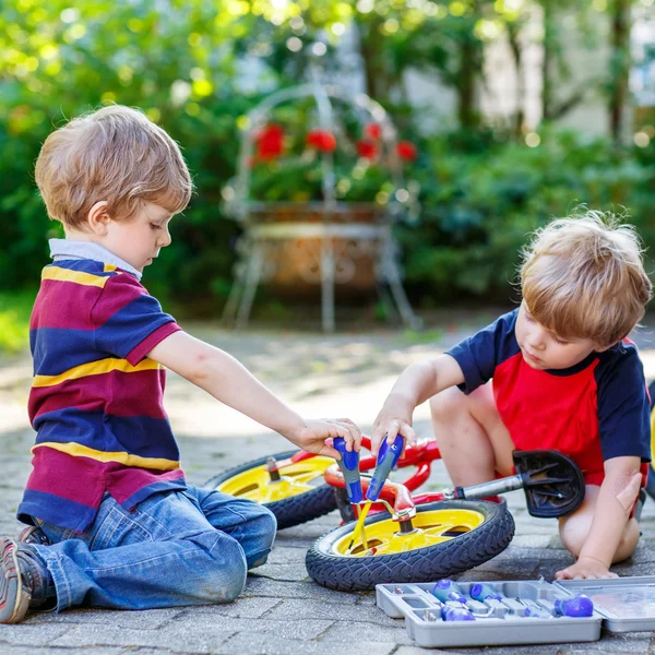 Vader onderwijs twee kleine jongen jongens om te herstellen van de ketting op fietsen — Stockfoto