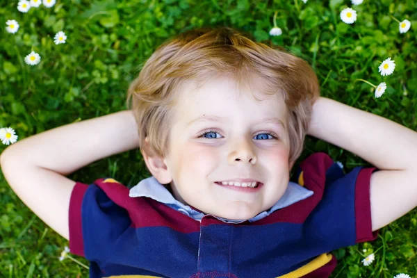 Glad liten blond pojke med blå ögon om på gräset — Stockfoto