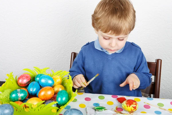 Kleiner Junge bemalt bunte Eier für Osterjagd — Stockfoto