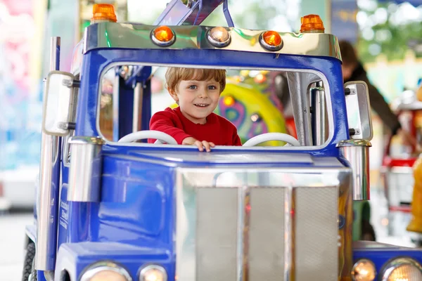 Grappige kleine jongen-jongen rijden op een merry-go-round carrousel — Stockfoto