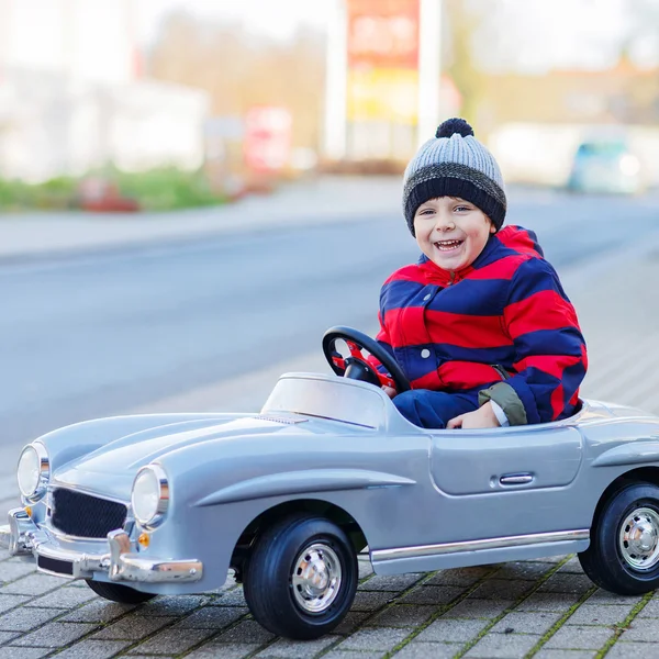 Joyeux petit garçon conduisant une grosse voiture jouet et s'amusant, en plein air — Photo