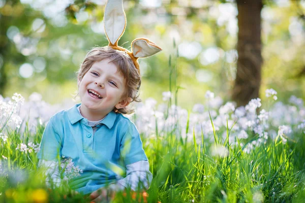 Bonito menino feliz vestindo orelhas de coelho de Páscoa na primavera verde — Fotografia de Stock