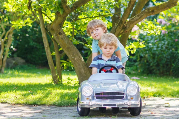 Deux garçons jumeaux heureux jouant avec la voiture jouet — Photo