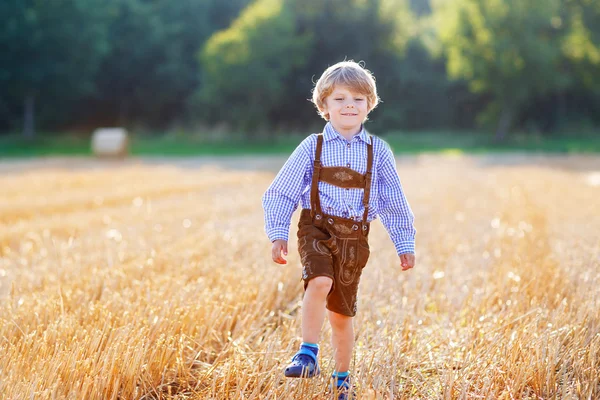 Lustiger kleiner Junge in Lederhosen, der durch Weizenfi läuft — Stockfoto