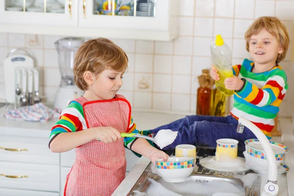 Two little lovely and funny kid boys washing dishes in domestic — Stock Photo, Image