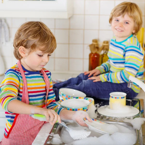 Dos gemelos rubios chicos lavando platos en la cocina doméstica —  Fotos de Stock