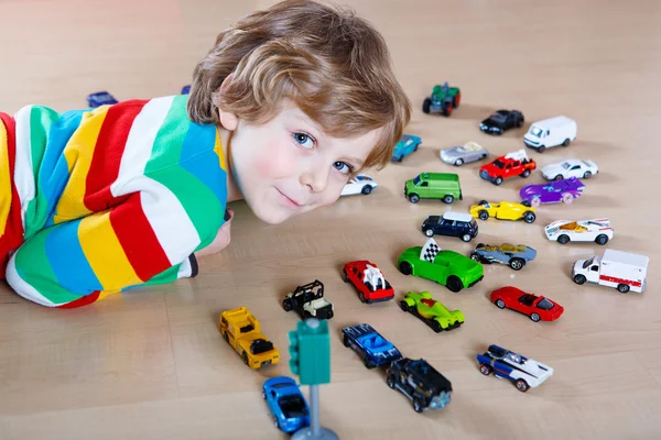 Little blond kid boy playing with lots of toy cars indoor — Stock Photo, Image